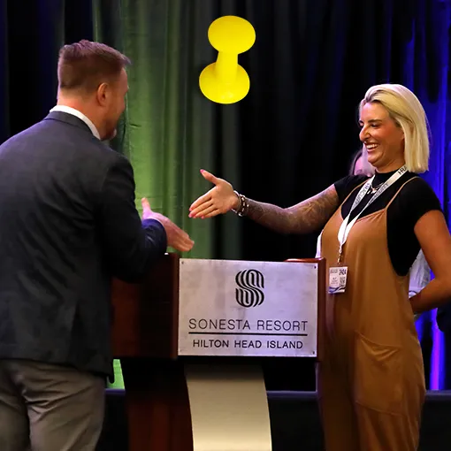 Two people shaking hands on stage at an ABA Cares conference